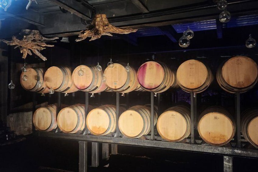 Wooden wine barrels arranged in rows on shelves. 3
