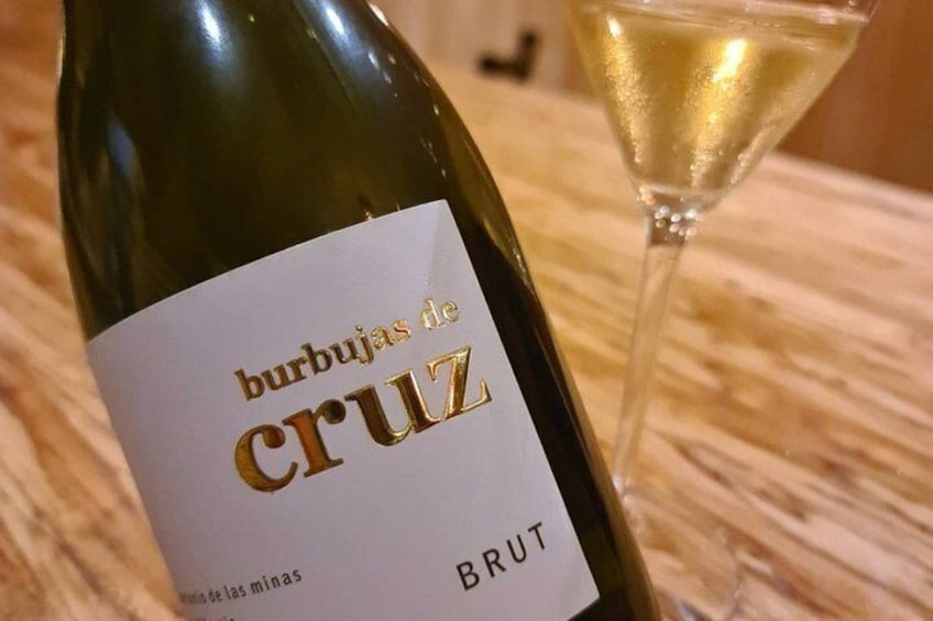 A bottle of burbujas de cruz brut wine with a glass of wine beside it. 4