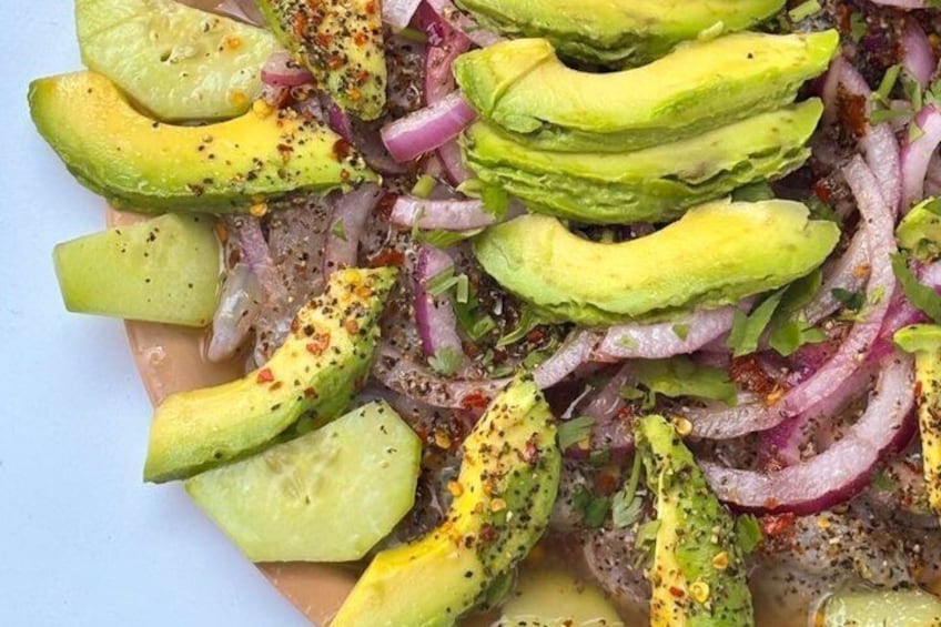 A dish with avocado slices, red onions, and a yellow sauce. 2