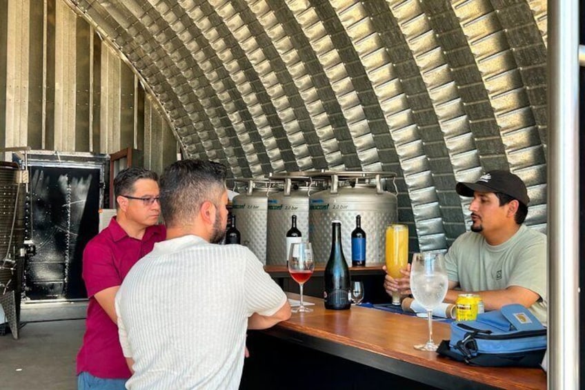 A bar with a curved ceiling, bottles of wine, and glasses on the counter. 4