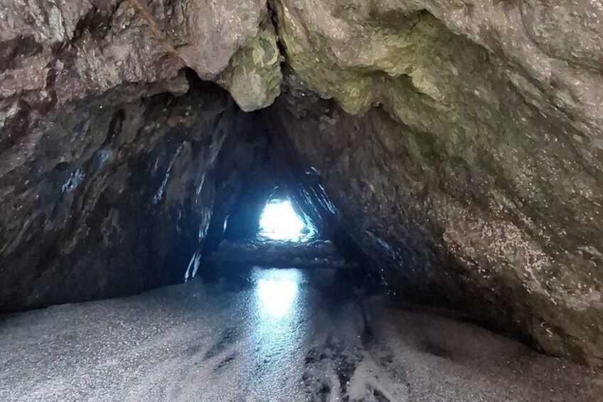 A cave with a wet floor and a light at the end. 5