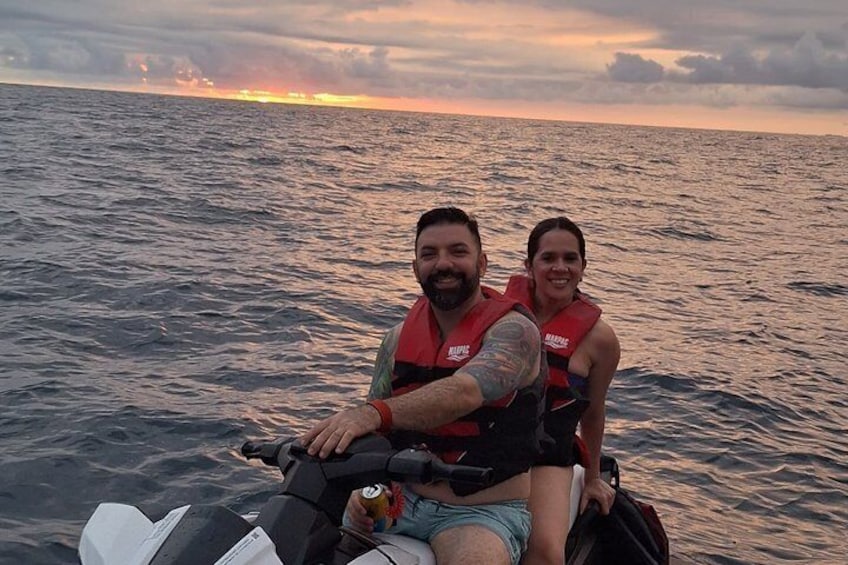 Two people on a jet ski in the ocean at sunset. 3