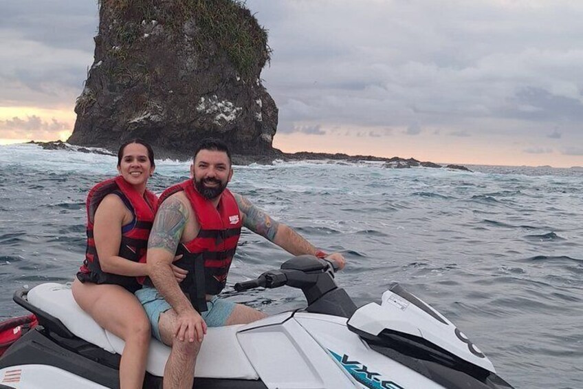 A person on a jet ski with a rocky outcrop in the background. 2
