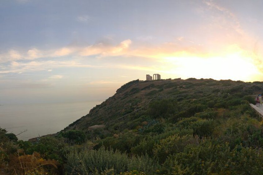 A coastal landscape with a hill, vegetation, and a structure on top. 1
