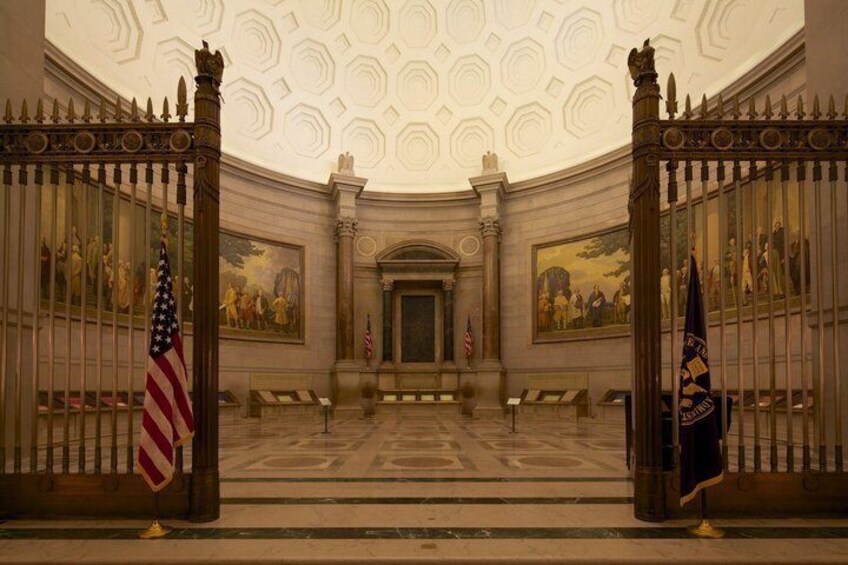 A grand hall with a high ceiling, ornate columns, and a central doorway flanked by flags. 3