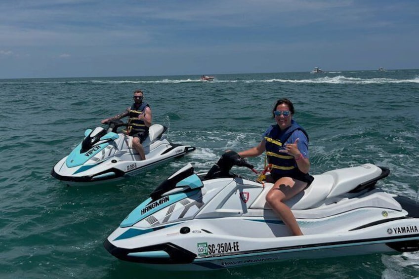 Two people on jet skis on a body of water with other boats in the background. 5