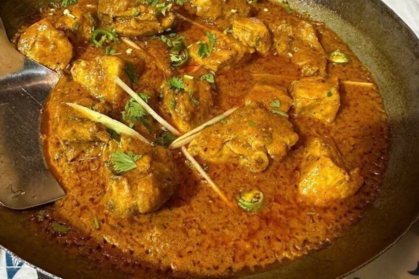 A dish of chicken curry with visible herbs and spices. 3