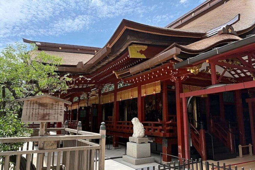 A traditional Japanese building with a wooden structure, a stone statue, and a red and gold roof. 1