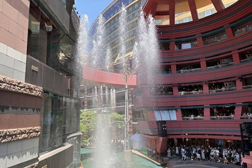 A multi-story building with a central water feature and a crowd of people. 3