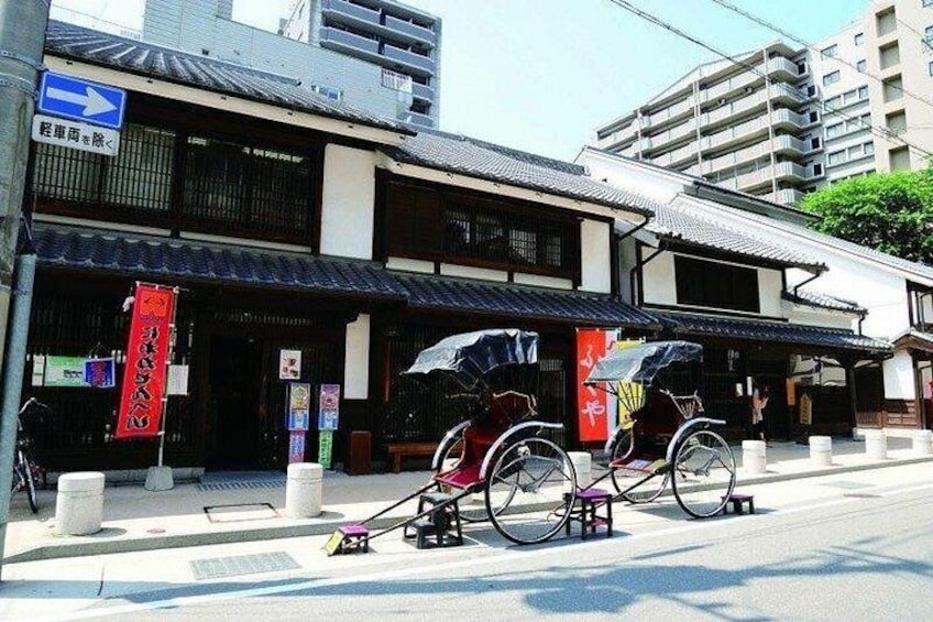A traditional Japanese building with a signboard, a bicycle, and a red banner. 5