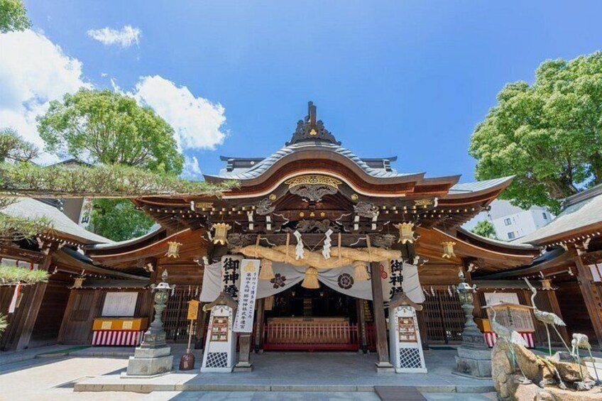A traditional Japanese temple entrance with ornate architecture, a red torii gate, and stone lanterns. 4