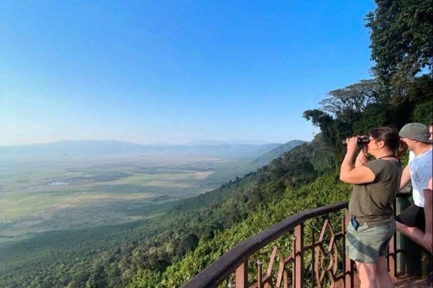 A person taking a photograph of a landscape with a forested hill and a distant view of a valley. 3