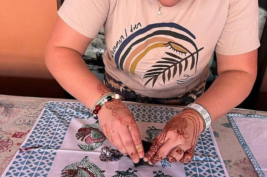 A person with henna designs on their hands, sitting at a table with a patterned tablecloth. 3