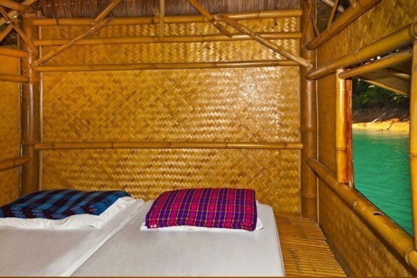 A bamboo room with a bed and a view of a beach. 5