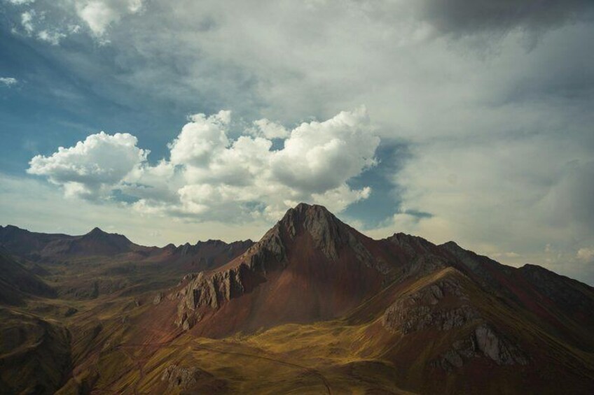 A mountain range with a prominent peak under a partly cloudy sky. 2