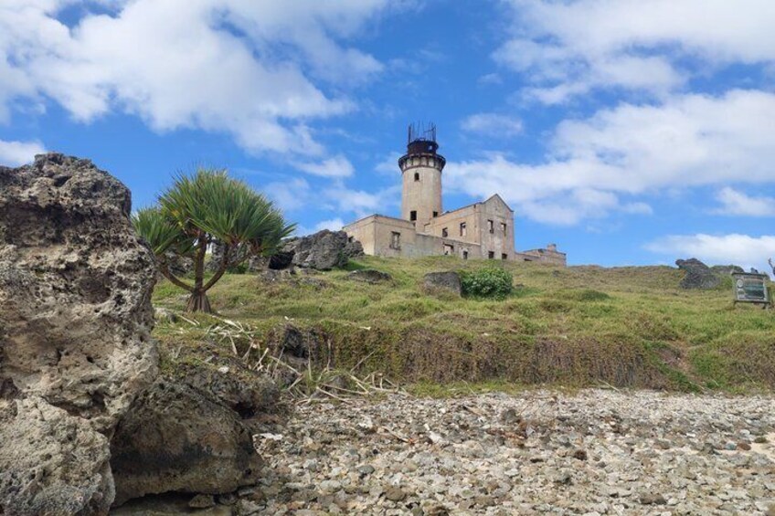 A lighthouse on a grassy hill with a clear sky. 1