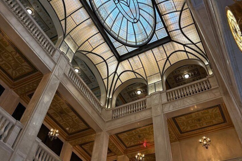A grand interior with a glass dome ceiling, ornate columns, and chandeliers. 4