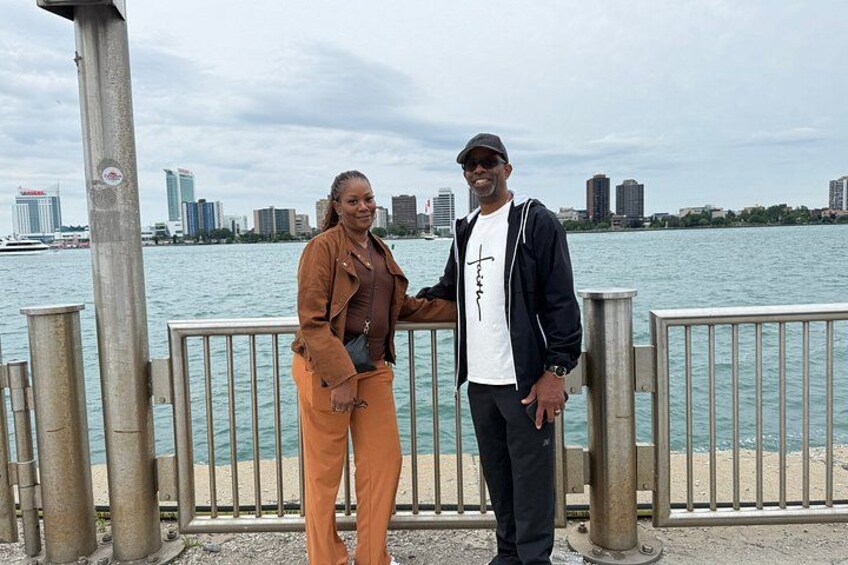 Two people standing by a waterfront with a city skyline in the background. 5