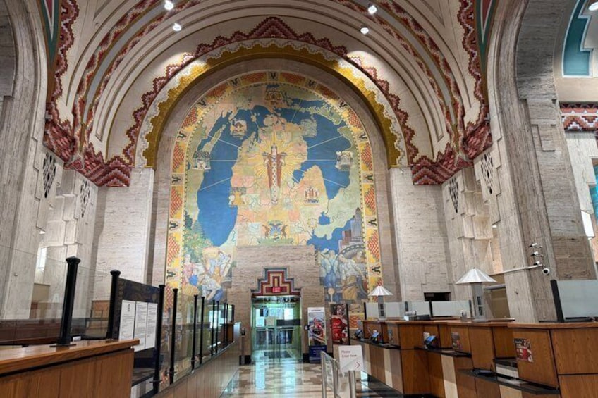 A church interior with a large mosaic on the wall, wooden pews, and a tiled floor. 2