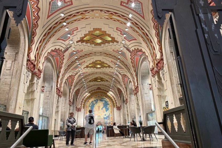 An interior of a cathedral with ornate ceilings, a central altar, and a few people. 5