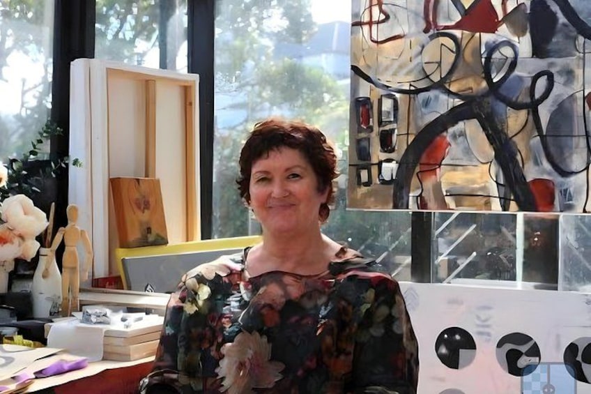 A person in a room with a painting, a wooden sculpture, and a vase with flowers. 2