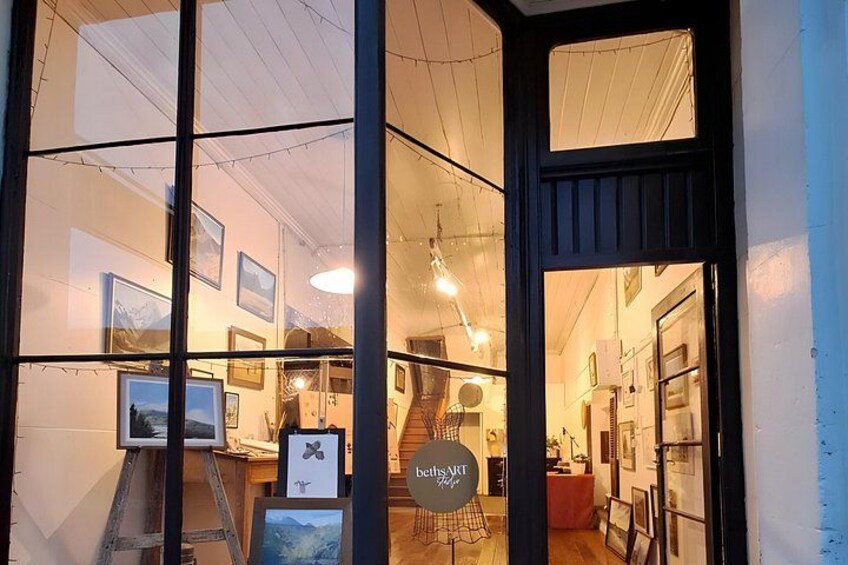 A gallery with framed artwork on the walls, a staircase, and a sign reading 'belleART.' 1