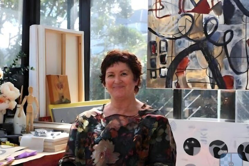 A person in a room with a painting, a wooden sculpture, and a vase with flowers. 2