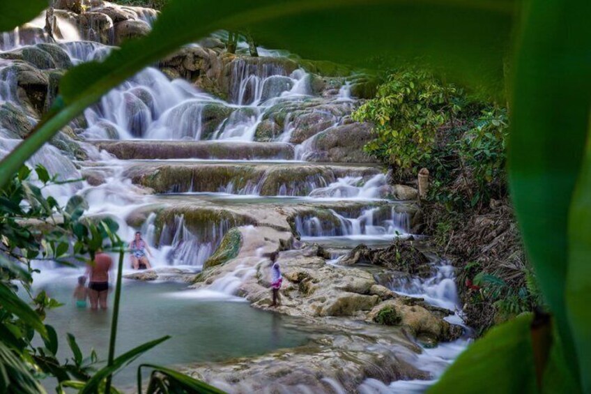 A multi-tiered waterfall with a person standing on a rock in the foreground. 3