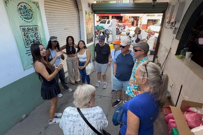 A group of people standing on a sidewalk, a QR code on a wall, and a storefront with a closed shutter. 5