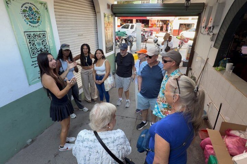 A group of people standing on a sidewalk, a QR code on a wall, and a closed shop with a green awning. 5