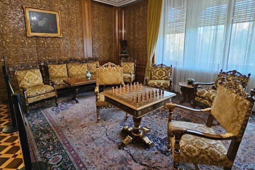 A room with ornate furniture, a chessboard, and a patterned rug. 5