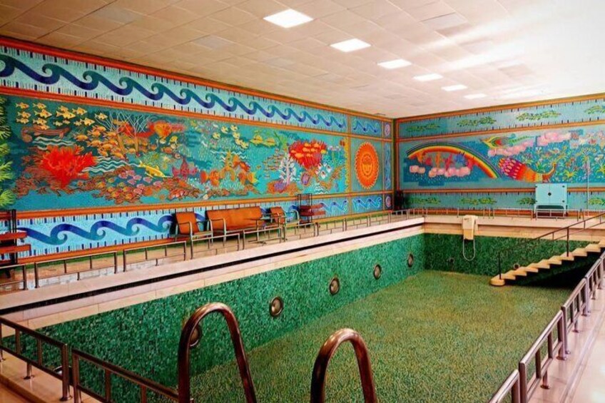 A swimming pool with a colorful mural on the walls and a green floor. 3