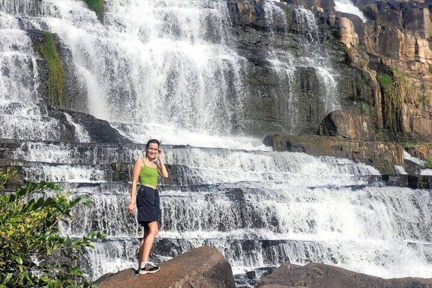 A waterfall with a person standing on a rock in front. 1