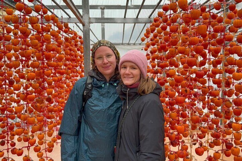 Two people standing in front of a structure with rows of orange objects. 4