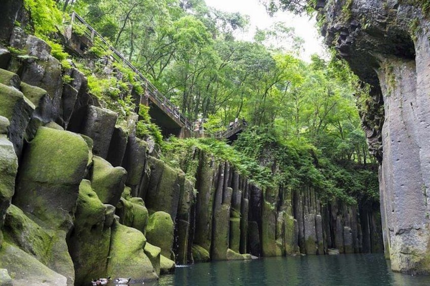 A forested area with large rock formations and a water body. 2