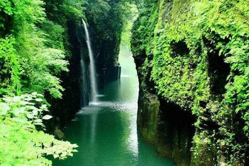 A waterfall in a lush green canyon. 4