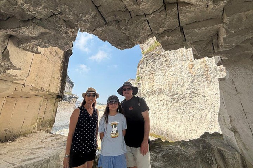 A group of people standing in front of a natural rock formation with a clear sky in the background. 5