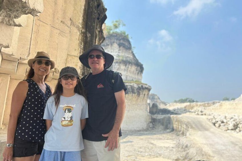 A family standing in front of a large rock formation with a clear sky. 5