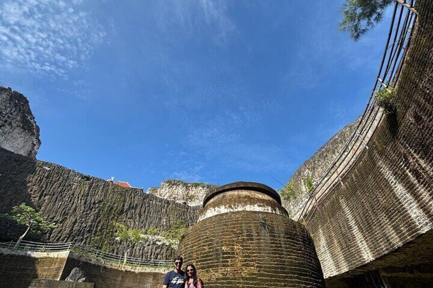 A historical fortification with a large central tower, steep cliffs, and a clear blue sky. 4