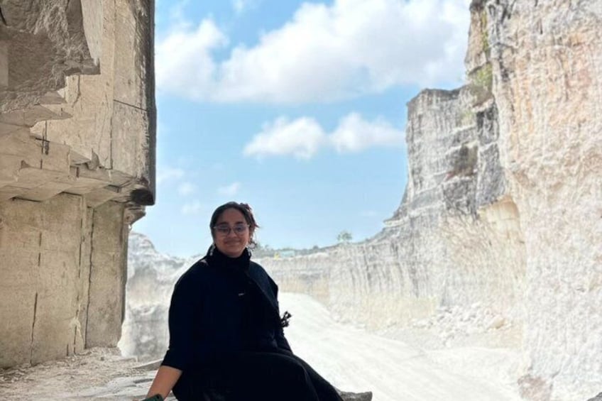 A person sitting in a narrow passageway between large rock formations. 3