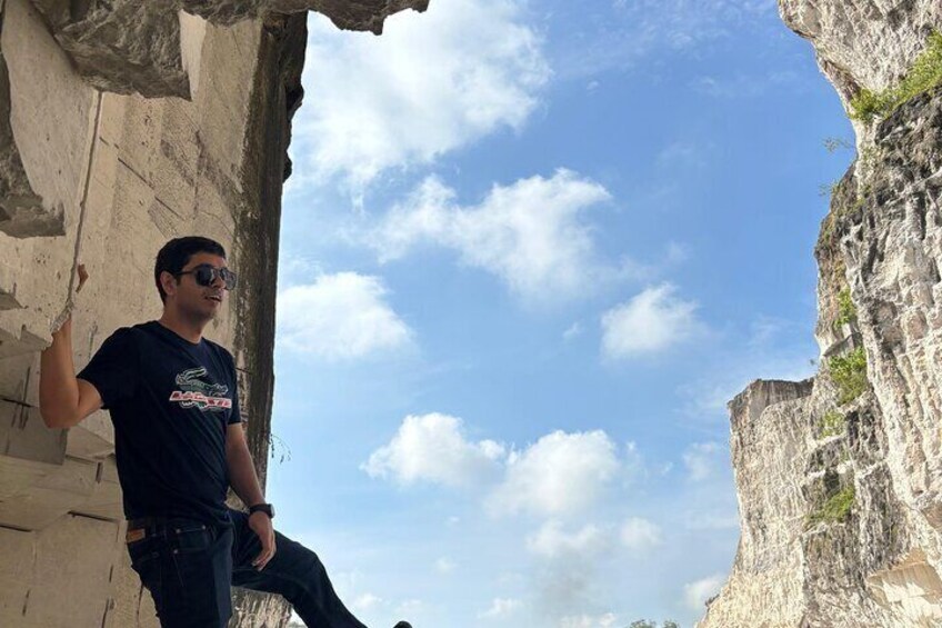 A person standing on a rocky ledge with a clear sky in the background. 5