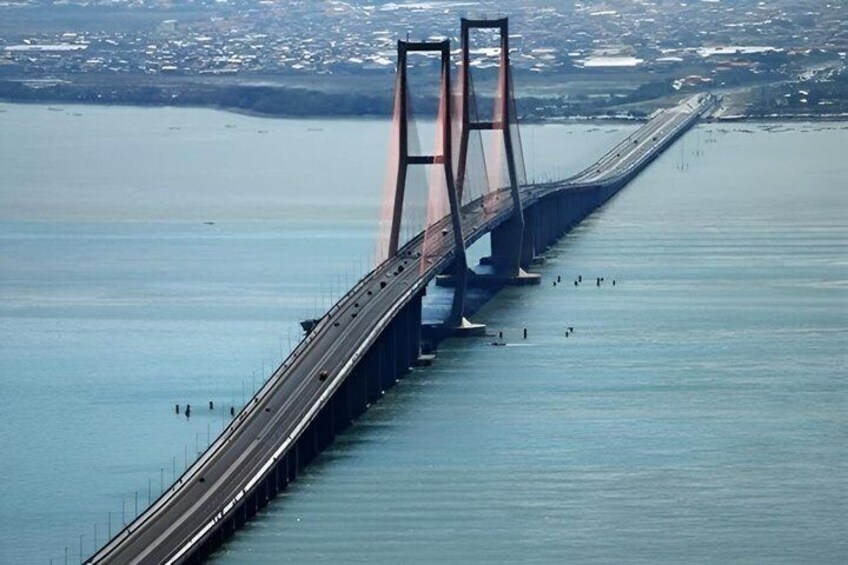 A long bridge spanning a body of water with a cityscape in the background. 2