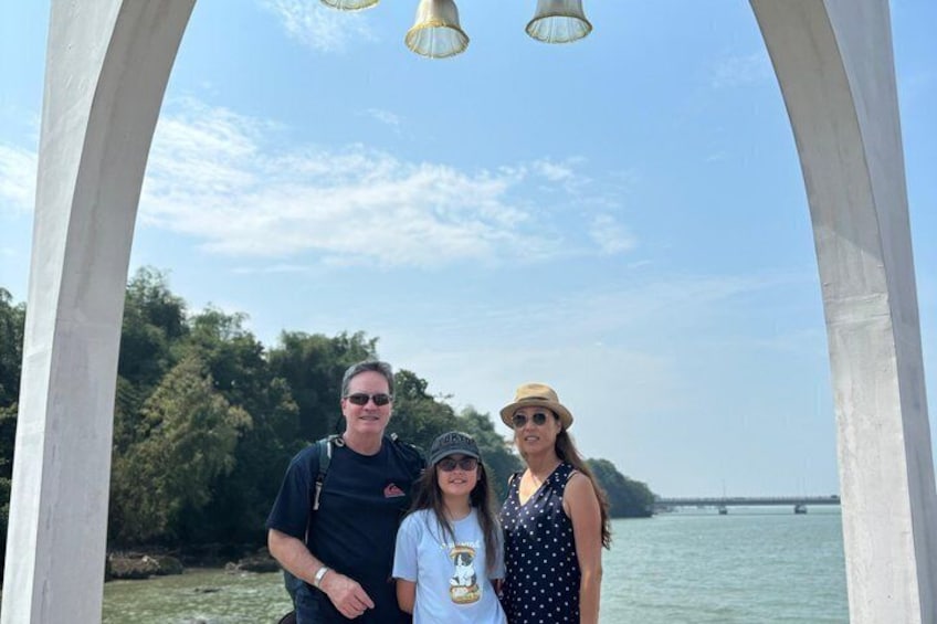 A family standing under a white archway with a river and bridge in the background. 4