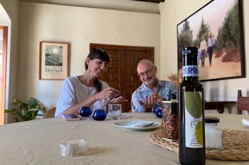 A table with a bottle of Basilico olive oil, a framed picture of Sevilla, and a blue decorative item. 3