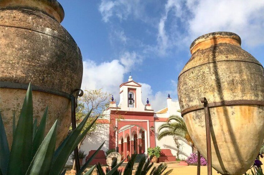 Large ceramic pots, a red building with a bell tower, and a clear blue sky. 1