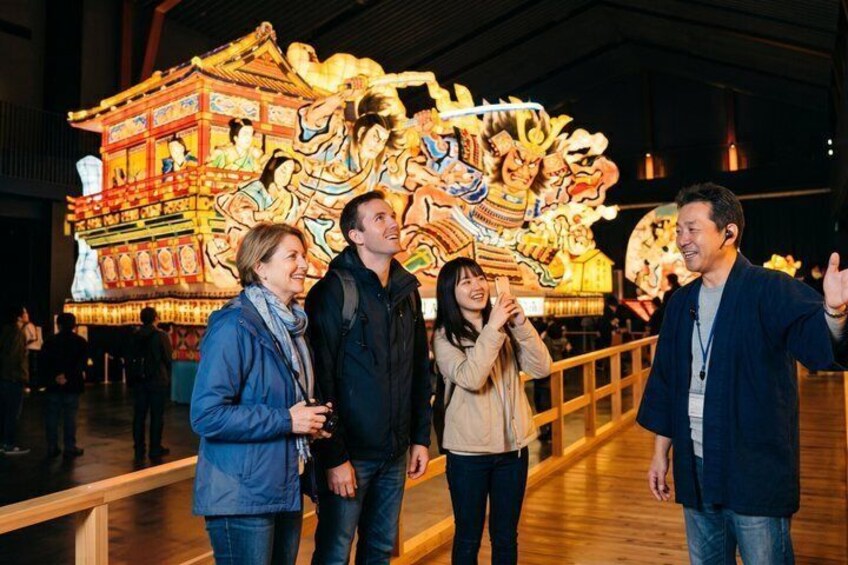 A group of people standing in front of a large, colorful traditional Chinese architectural structure. 1