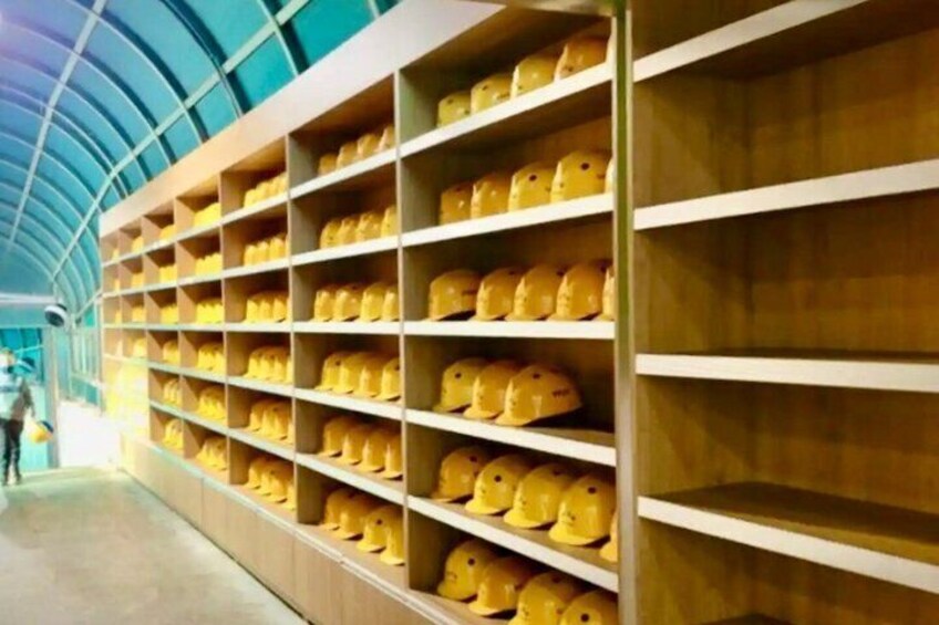 A large number of yellow helmets on shelves in a warehouse. 1