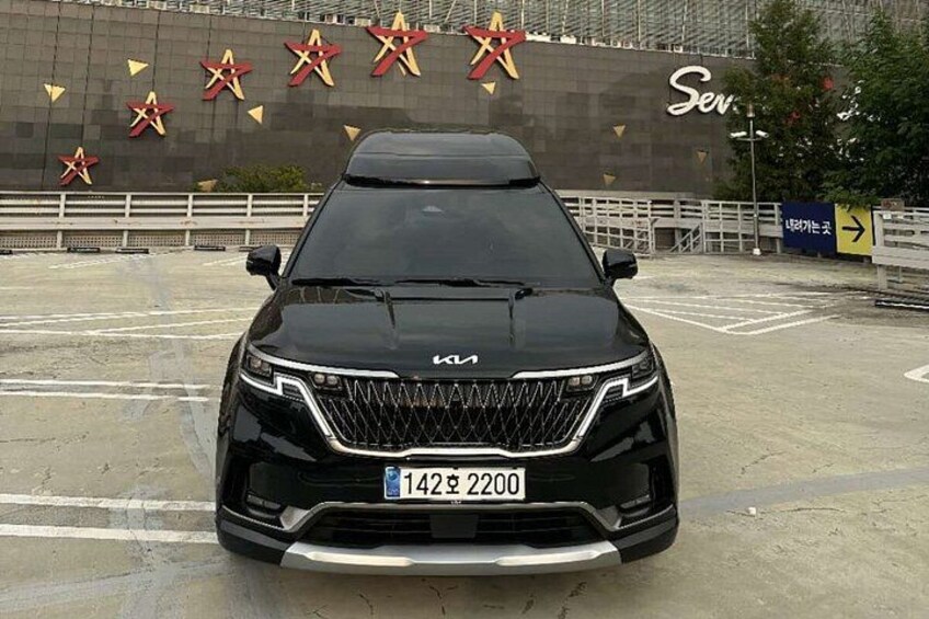 A black Kia SUV parked in a parking lot with a large star-shaped sign in the background. 4