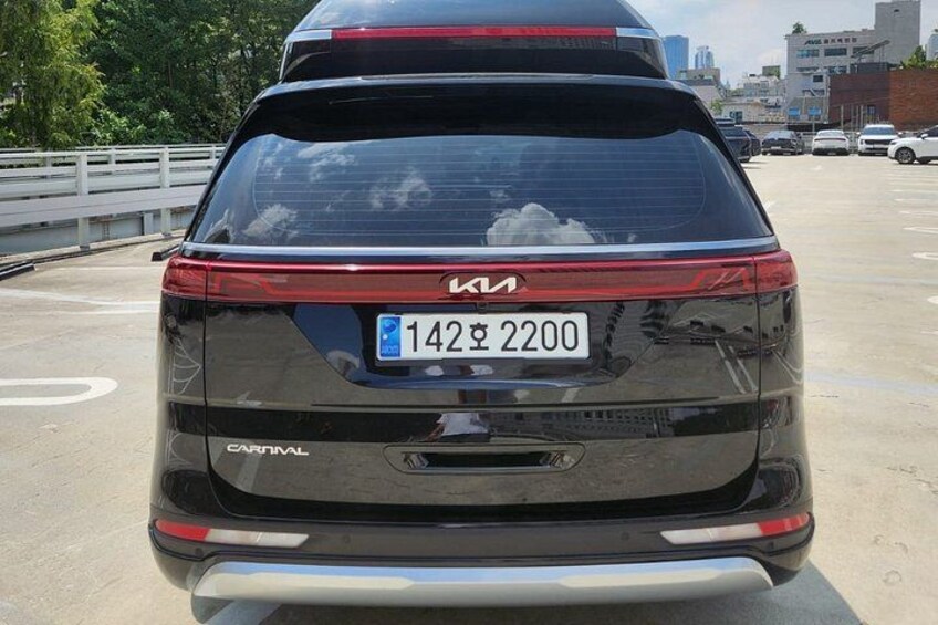 The rear of a black Kia Carnival SUV with a visible license plate. 3
