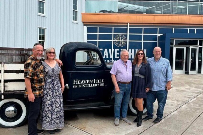 A group of people standing in front of a building with a truck labeled 'Heaven Hill Distillery.' 2